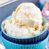 Two scoops of vanilla ice cream in a blue patterned bowl, topped with colorful sprinkles and a spoon nearby. The slightly blurred background highlights the creamy texture—a perfect treat inspired by easy ice cream recipes.